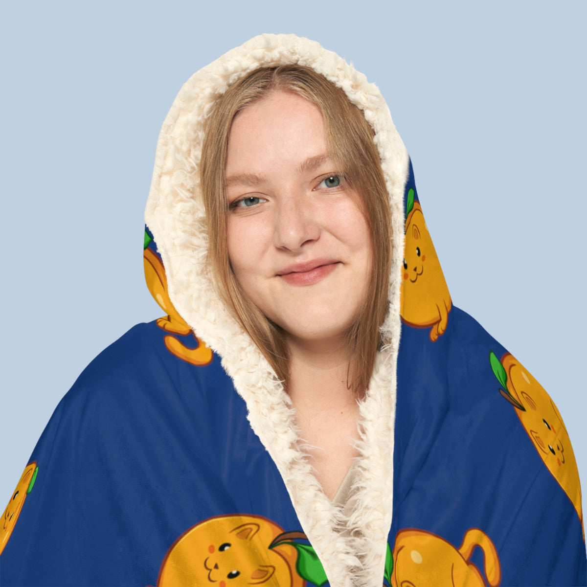 Happy woman wearing the dark blue Apricat⢠hooded sherpa blanket face zoomed in. Apricat⢠is an apricot drawn as a cute cat.