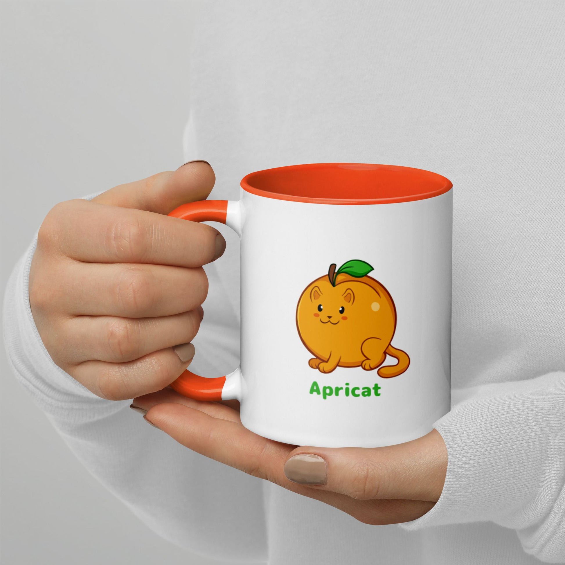 Hands holding a white and orange Coffee Mug with Apricat⢠print. Apricat⢠is an apricot drawn as a cute cat.