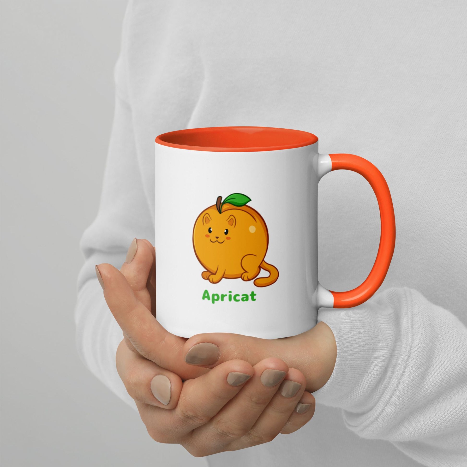 Hands holding a white and orange Coffee Mug with Apricat⢠print. Apricat⢠is an apricot drawn as a cute cat.