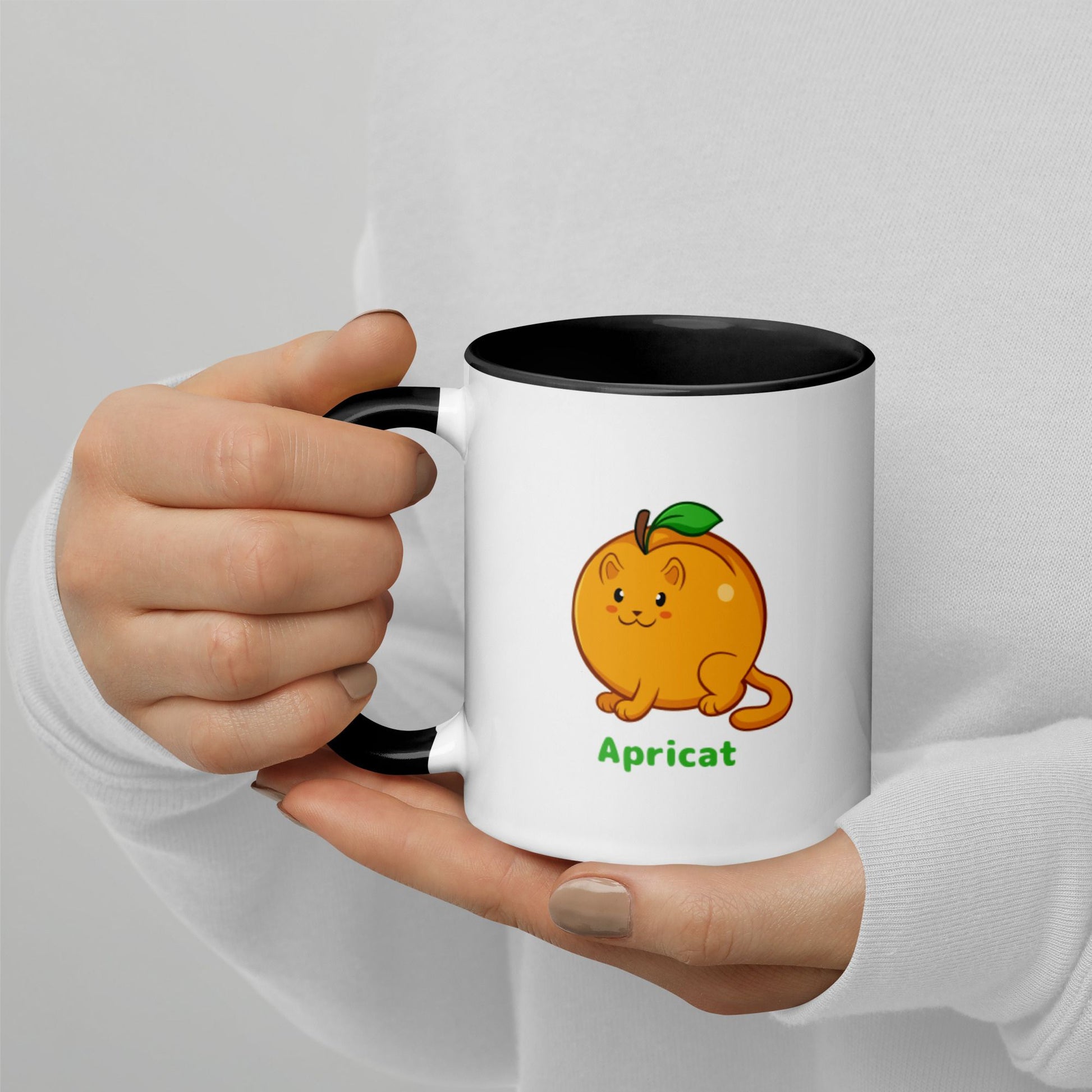 Hands holding a white and black Coffee Mug with Apricat⢠print. Apricat⢠is an apricot drawn as a cute cat.
