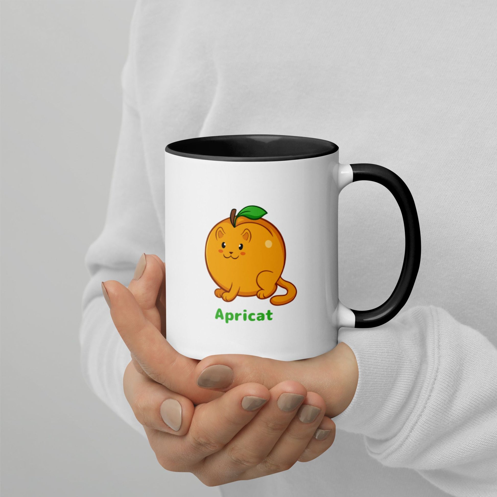 Hands holding a white and black Coffee Mug with Apricat⢠print. Apricat⢠is an apricot drawn as a cute cat.