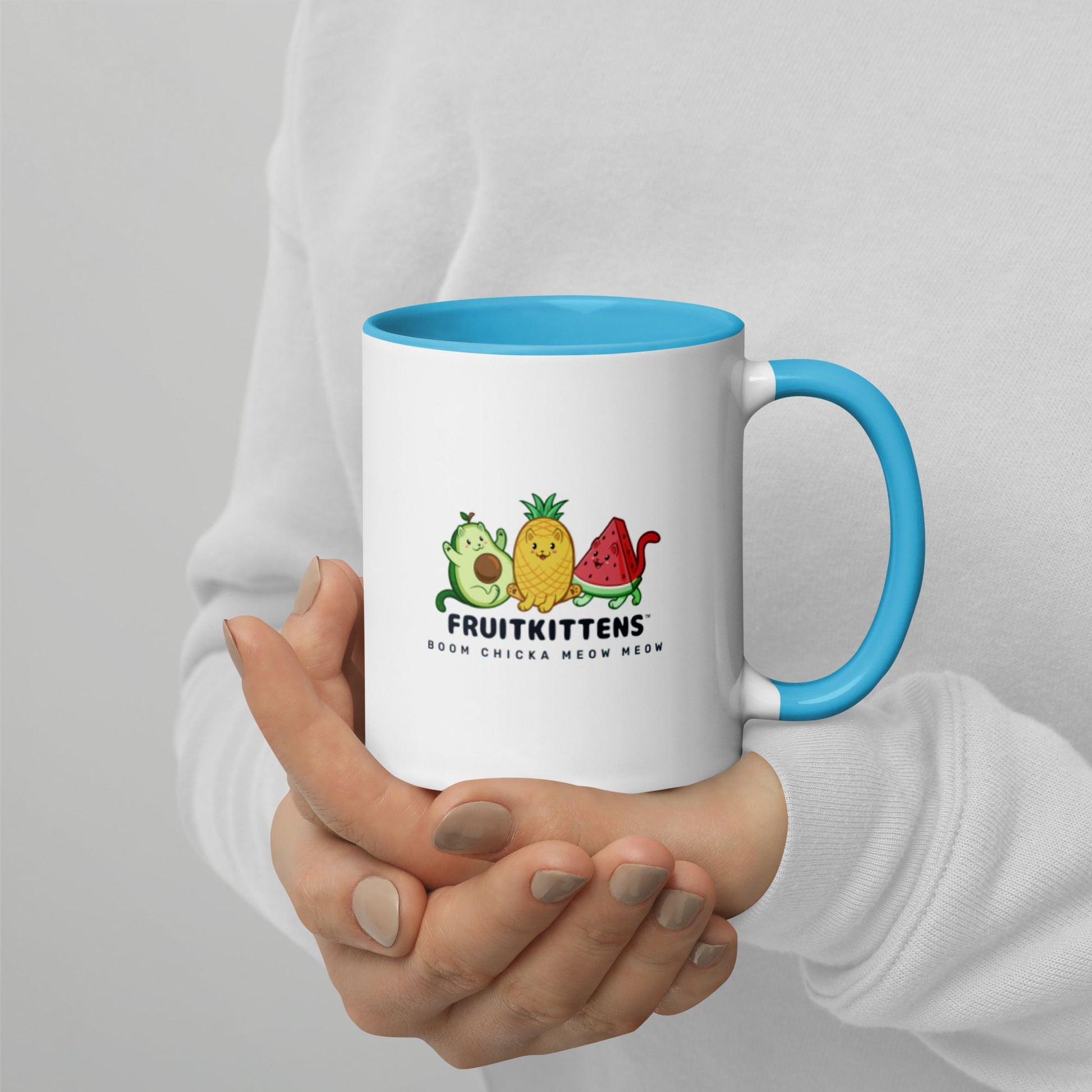 Hands holding a white and blue Coffee Mug with with Fruitkittens⢠logo. Fruitkittens⢠are fruits drawn as cute cats. The logo features Pawocadoâ˘, Pawnapple⢠and Watermewlonâ˘