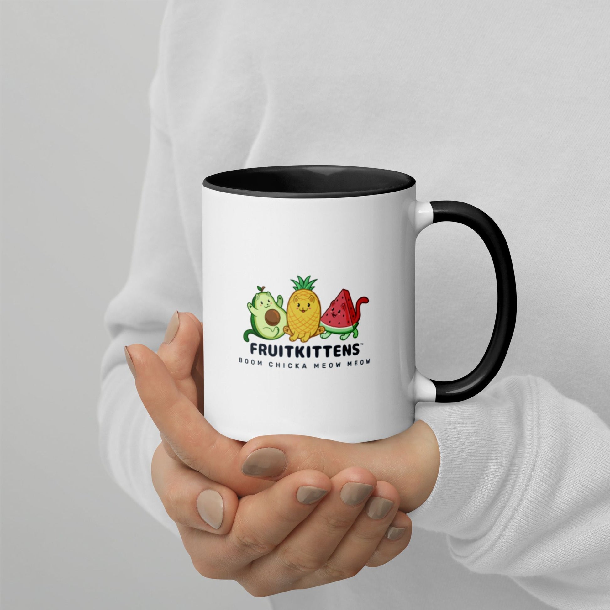 Hands holding a white and black Coffee Mug with with Fruitkittens⢠logo. Fruitkittens⢠are fruits drawn as cute cats. The logo features Pawocadoâ˘, Pawnapple⢠and Watermewlonâ˘