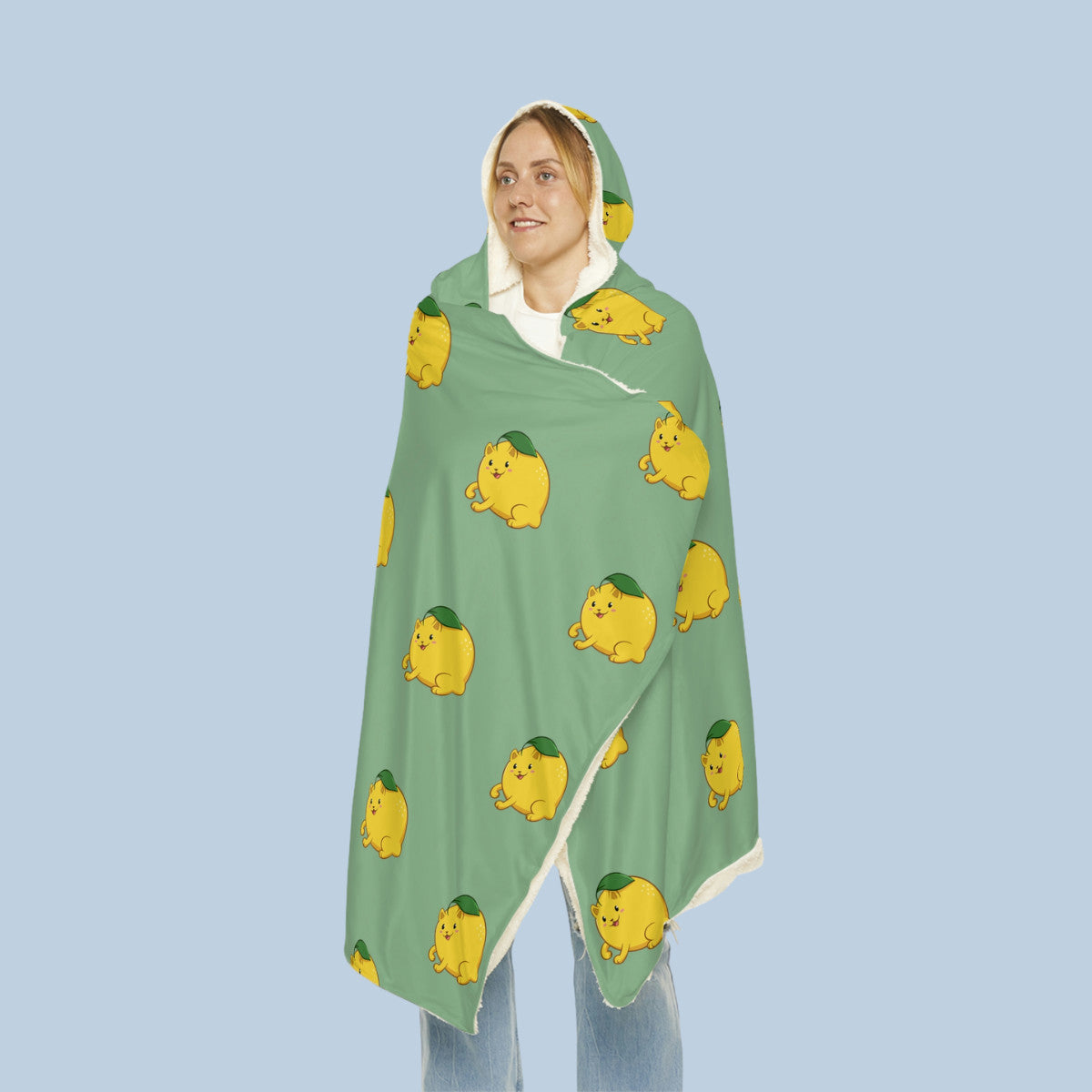 Happy woman wearing the light green Lemeow⢠hooded microfiber fleece blanket seen from front. Lemeow⢠is a lemon drawn as a cute cat.