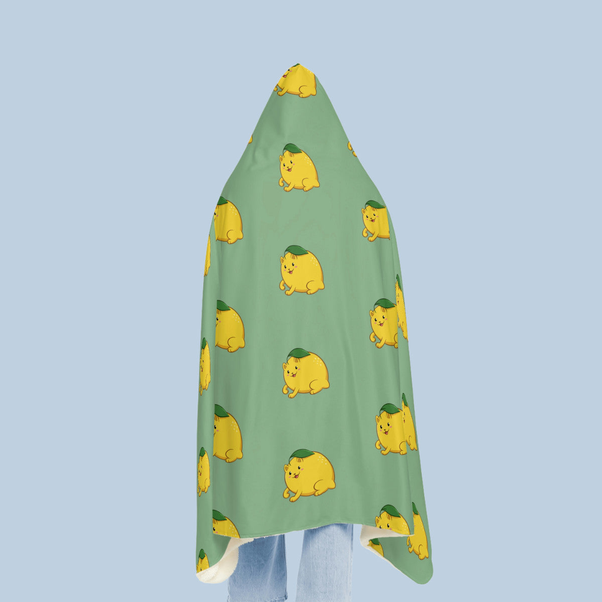 Happy woman wearing the light green Lemeow⢠hooded microfiber fleece blanket seen from behind. Lemeow⢠is a lemon drawn as a cute cat.