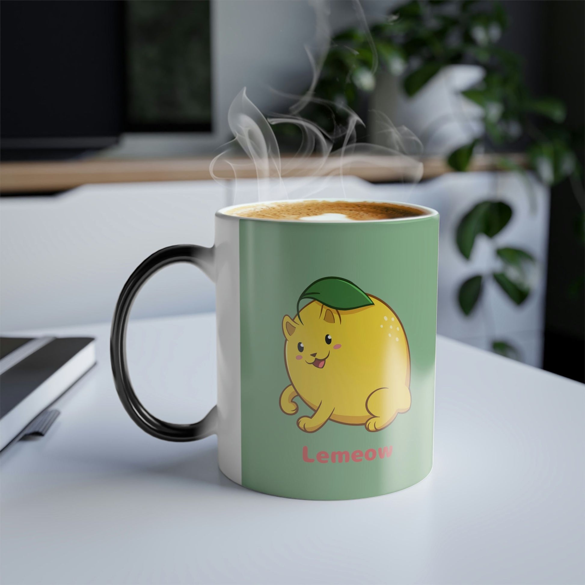 Light Green Magic Mug with Lemeow⢠print standing on an office desk. Lemeow⢠is a lemon drawn as a cute cat.