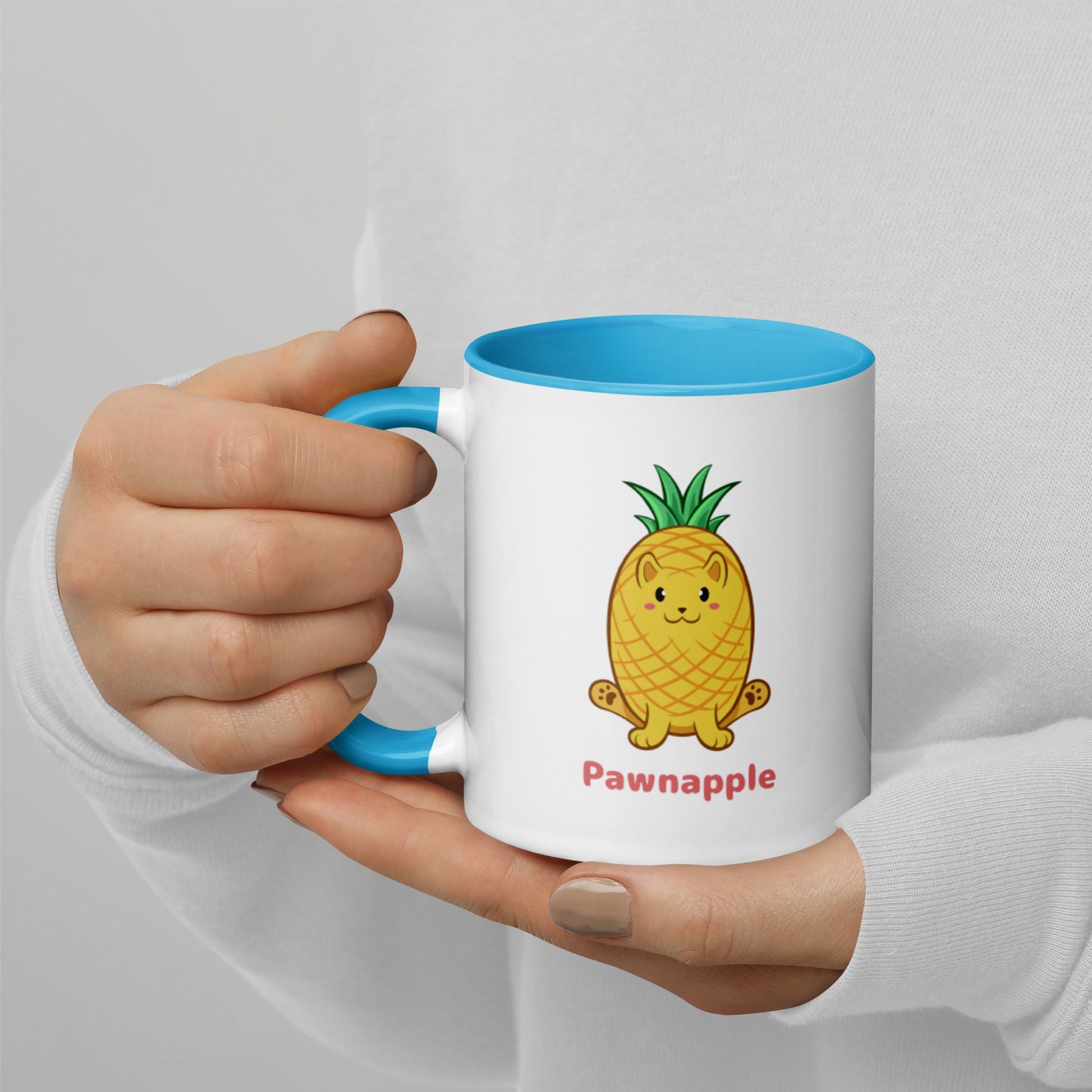 Hands holding a white and blue Coffee Mug with Pawnapple⢠print. Pawnapple⢠is a pineapple drawn as a cute cat.