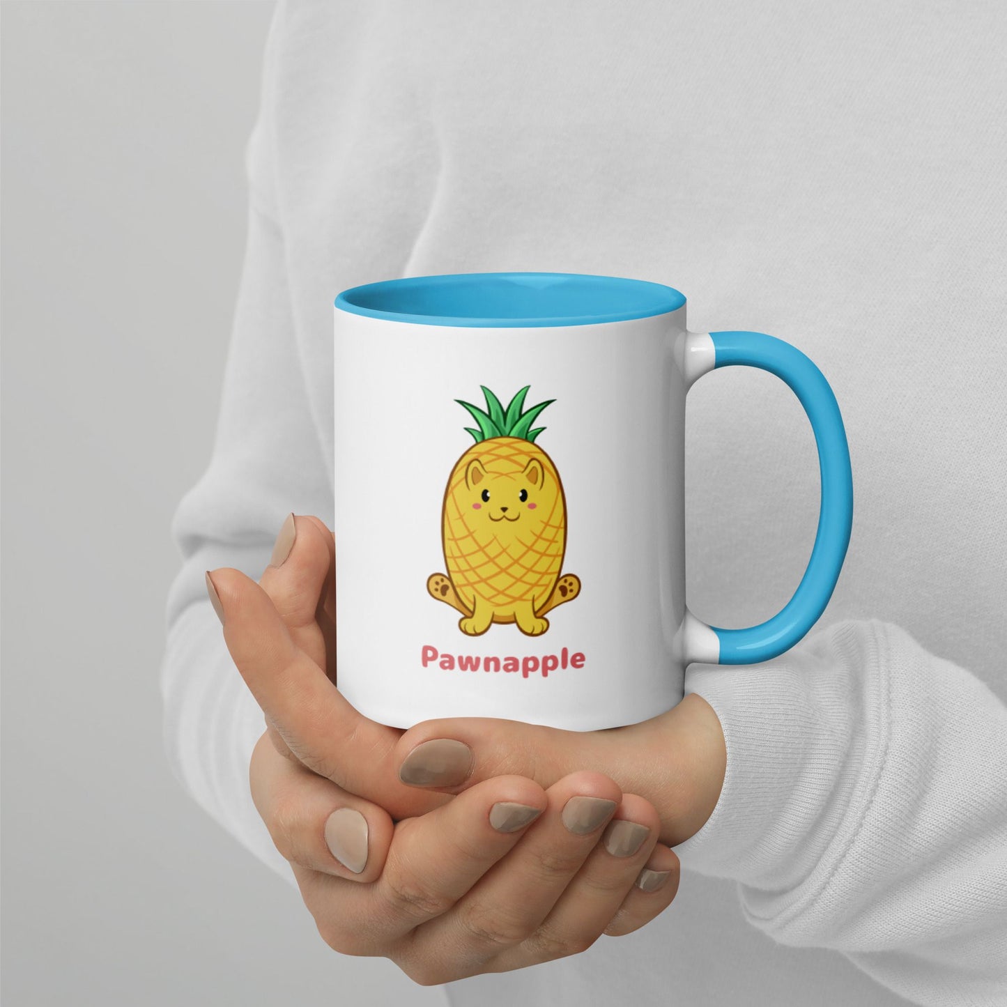 Hands holding a white and blue Coffee Mug with Pawnapple⢠print. Pawnapple⢠is a pineapple drawn as a cute cat.