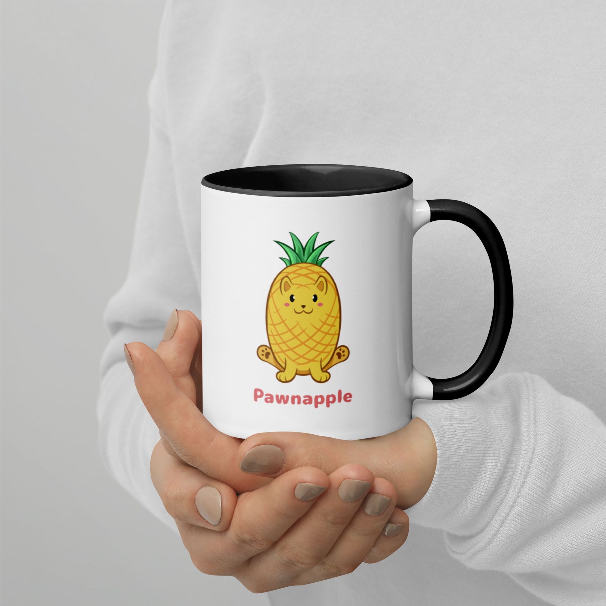 Hands holding a white and black Coffee Mug with Pawnapple⢠print. Pawnapple⢠is a pineapple drawn as a cute cat.