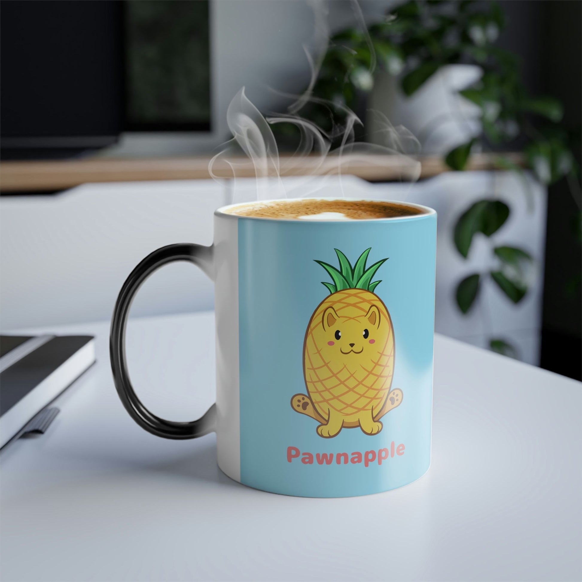Light Blue Magic Mug with Pawnapple⢠print standing on an office desk. Pawnapple⢠is a pineapple drawn as a cute cat.
