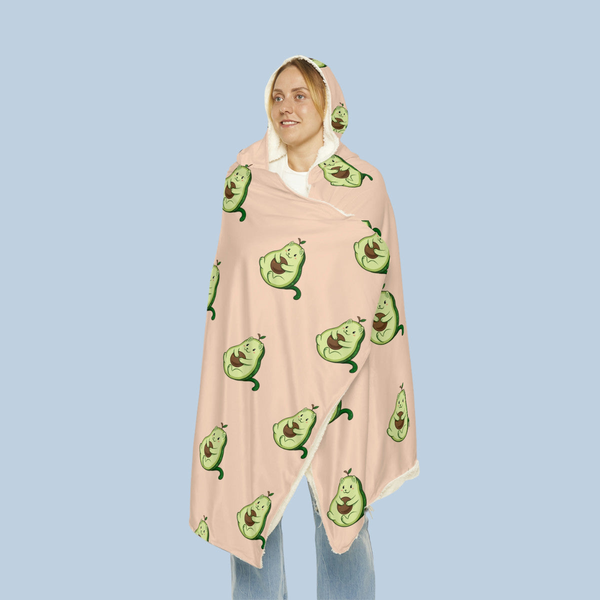 Happy woman wearing the beige Pawocado⢠hooded microfiber fleece blanket seen from front. Pawocado⢠is an avocado drawn as a cute cat.