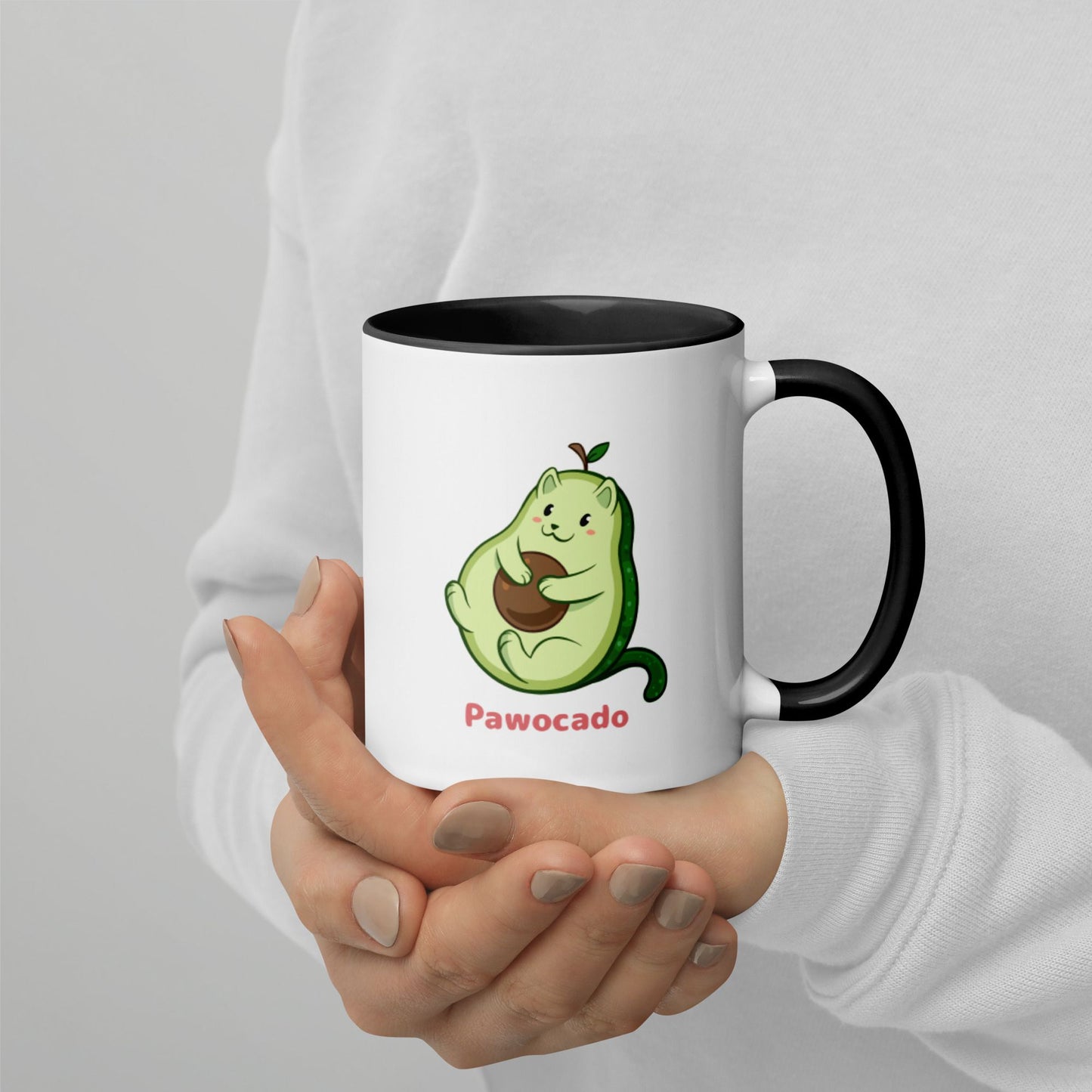 Hands holding a white and black Coffee Mug with Pawocado⢠print. Pawocado⢠is an avocado drawn as a cute cat.