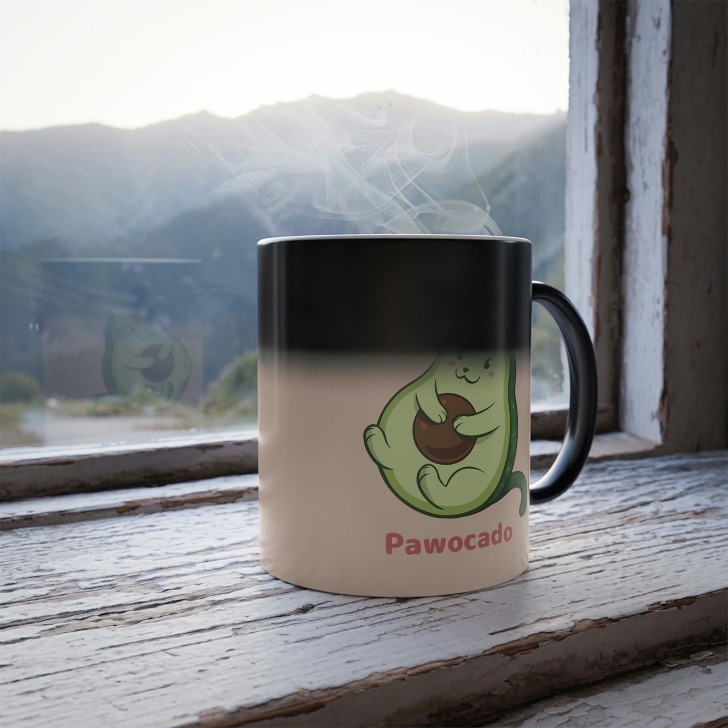 Beige Magic Mug with Pawocado⢠print standing in a window turning from black into the print. Pawocado⢠is an avocado drawn as a cute cat.