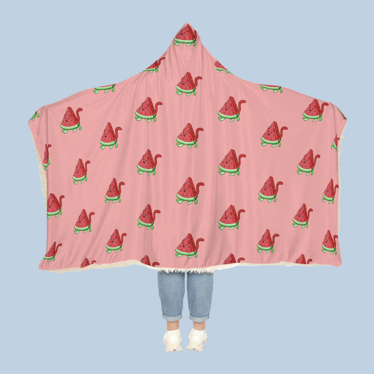 Happy woman wearing the pink Watermewlon⢠hooded sherpa blanket like a cape with arms stretched out seen from behind so that the full pattern is visible. Watermewlon⢠is a watermelon drawn as a cute cat.