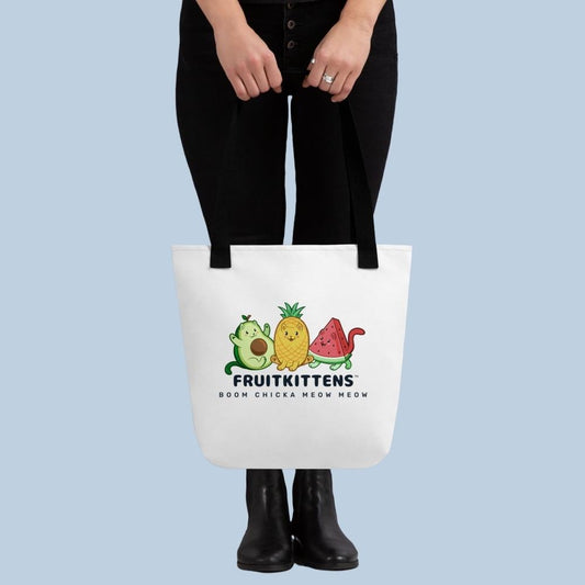 Person holding a white Tote Bag with Fruitkittens⢠logo. Fruitkittens⢠are fruits drawn as cute cats. The logo features Pawocadoâ˘, Pawnapple⢠and Watermewlonâ˘.