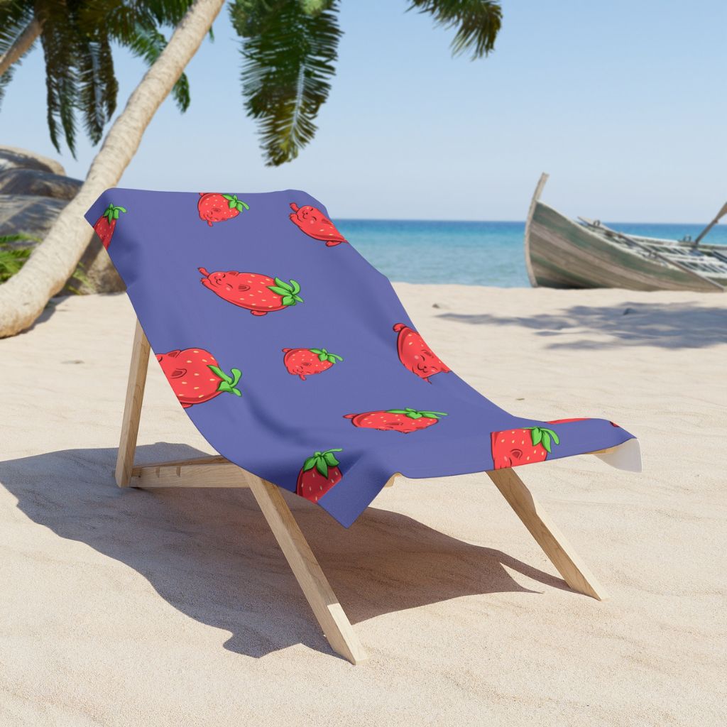 Purple Beach Towel with Clawberry™ print on a sunchair on sandy beach. Clawberry™ is a strawberry drawn as a cute cat.