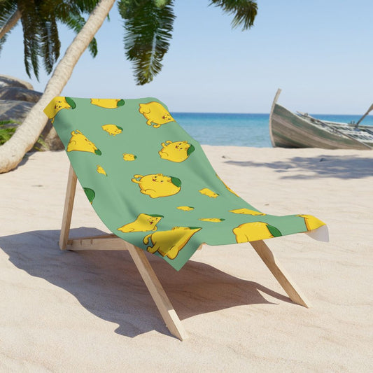 Light Green Beach Towel with Lemeow™ print on a sunchair on sandy beach. Lemeow™ is a lemon drawn as a cute cat.