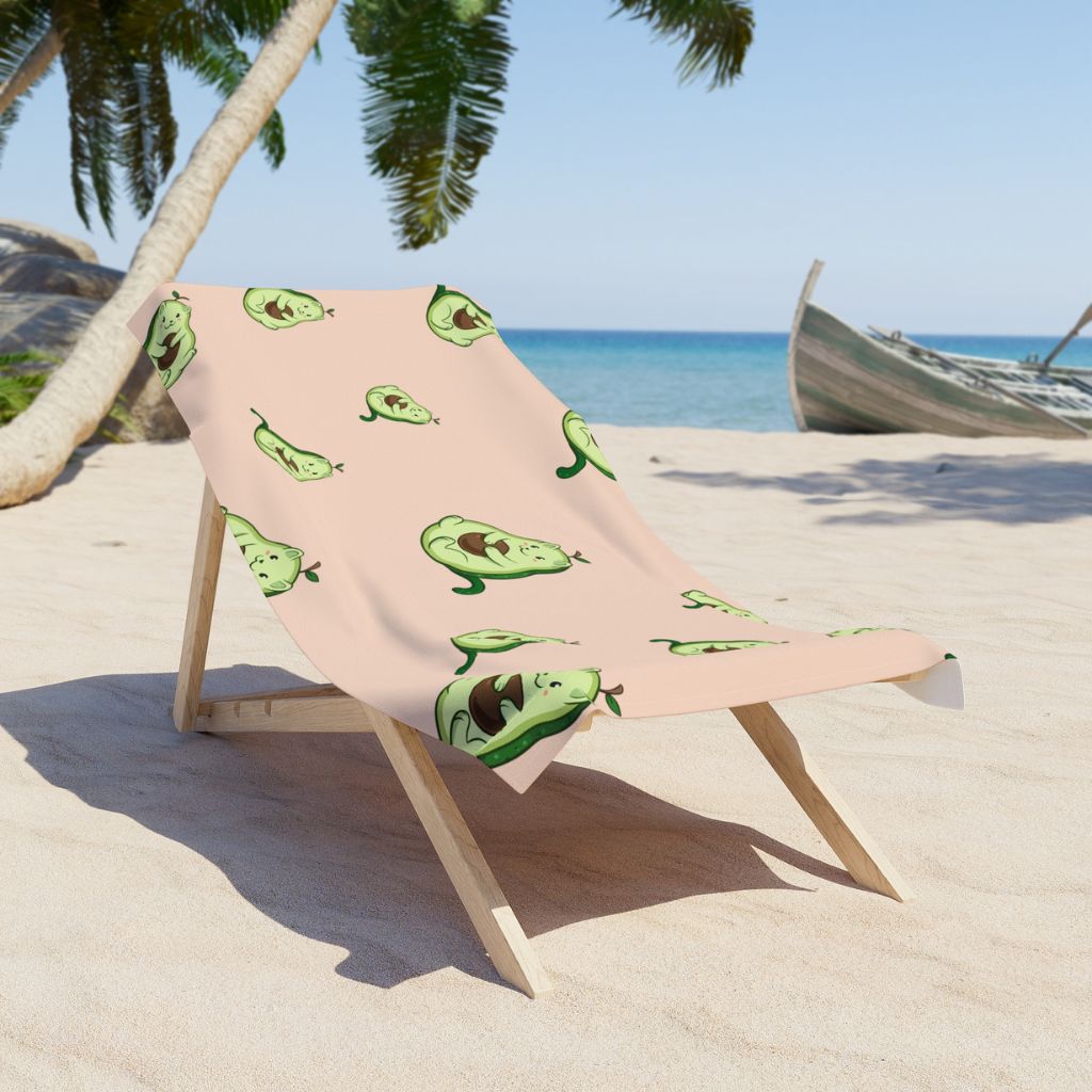 Beige Beach Towel with Pawocado™ print on a sunchair on sandy beach. Pawocado™ is an avocado drawn as a cute cat.