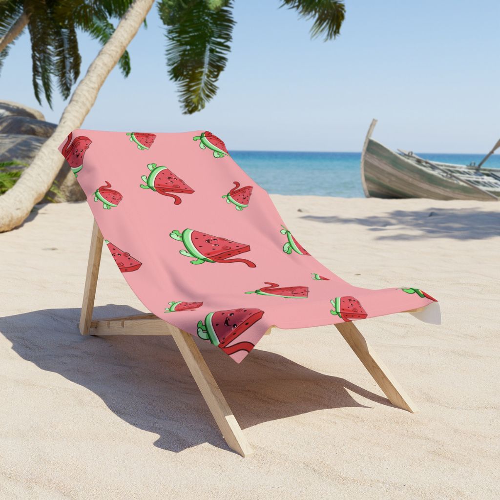 Pink Beach Towel with Watermewlon™ print on a sunchair on sandy beach. Watermewlon™ is a watermelon drawn as a cute cat.