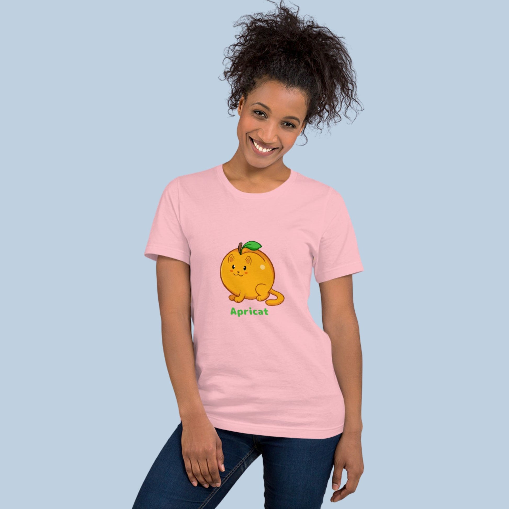 Woman wearing a pink T-Shirt with Apricat™ print. Apricat™ is an apricot drawn as a cute cat.