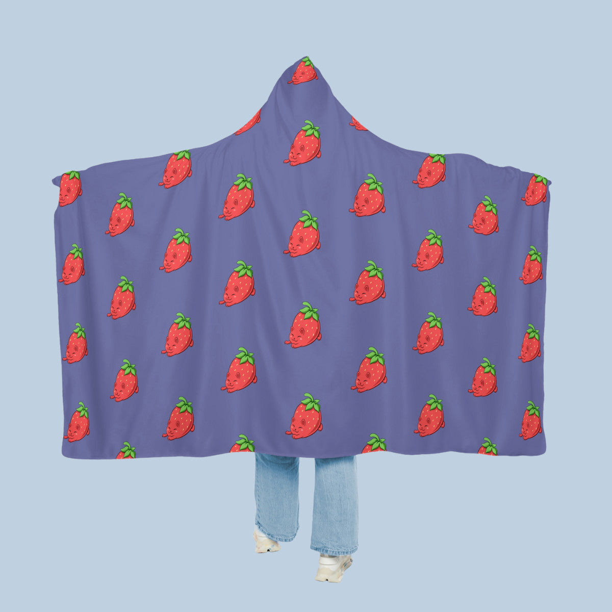 Happy woman wearing the purple Clawberry™ hooded microfiber fleece blanket like a cape with arms stretched out seen from behind so that the full pattern is visible. Clawberry™ is a strawberry drawn as a cute cat.