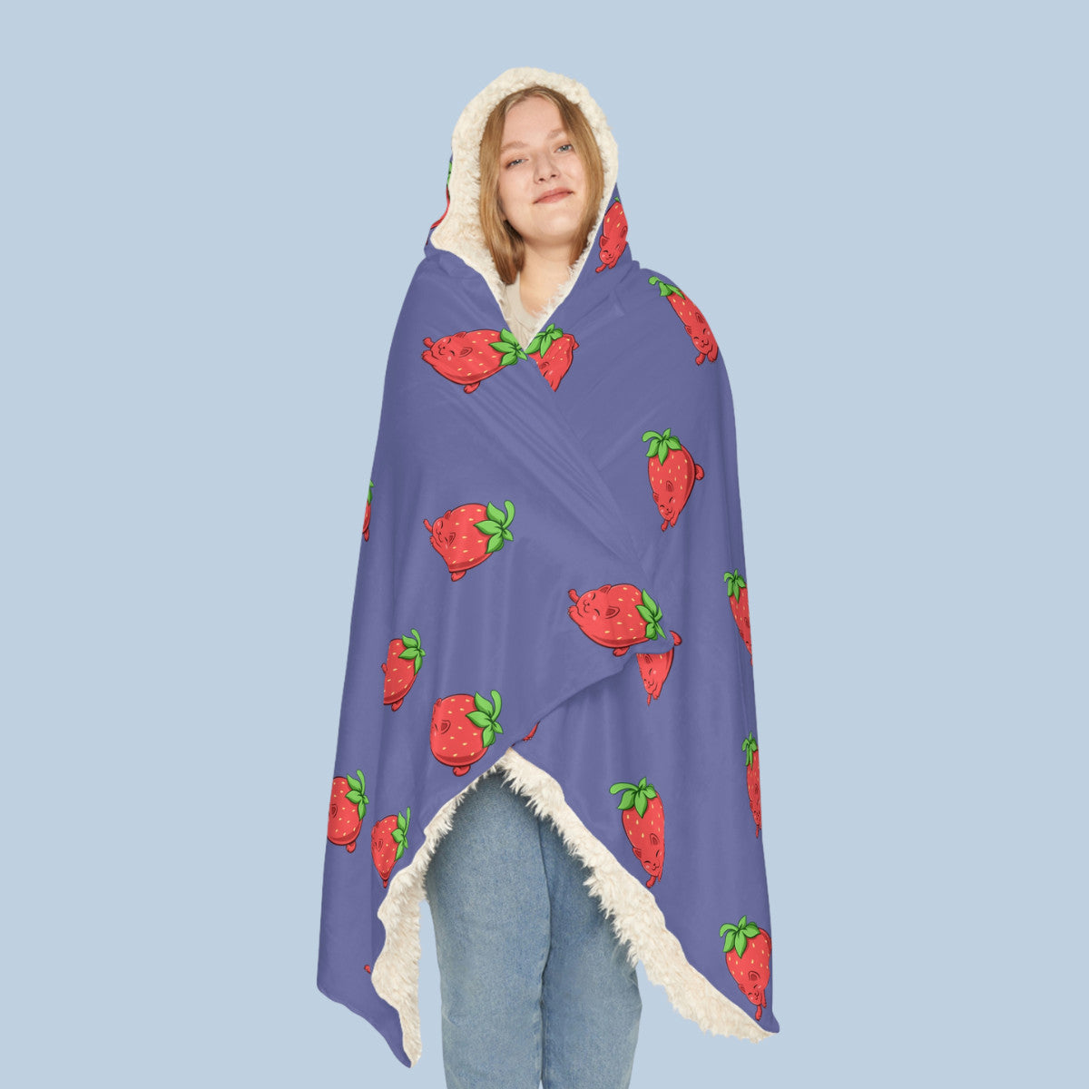 Happy woman wearing the purple Clawberry™ hooded sherpa blanket seen from front. Clawberry™ is a strawberry drawn as a cute cat.