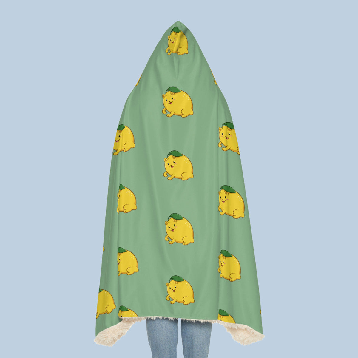 Happy woman wearing the light green Lemeow™ hooded sherpa blanket seen from behind. Lemeow™ is a lemon drawn as a cute cat.