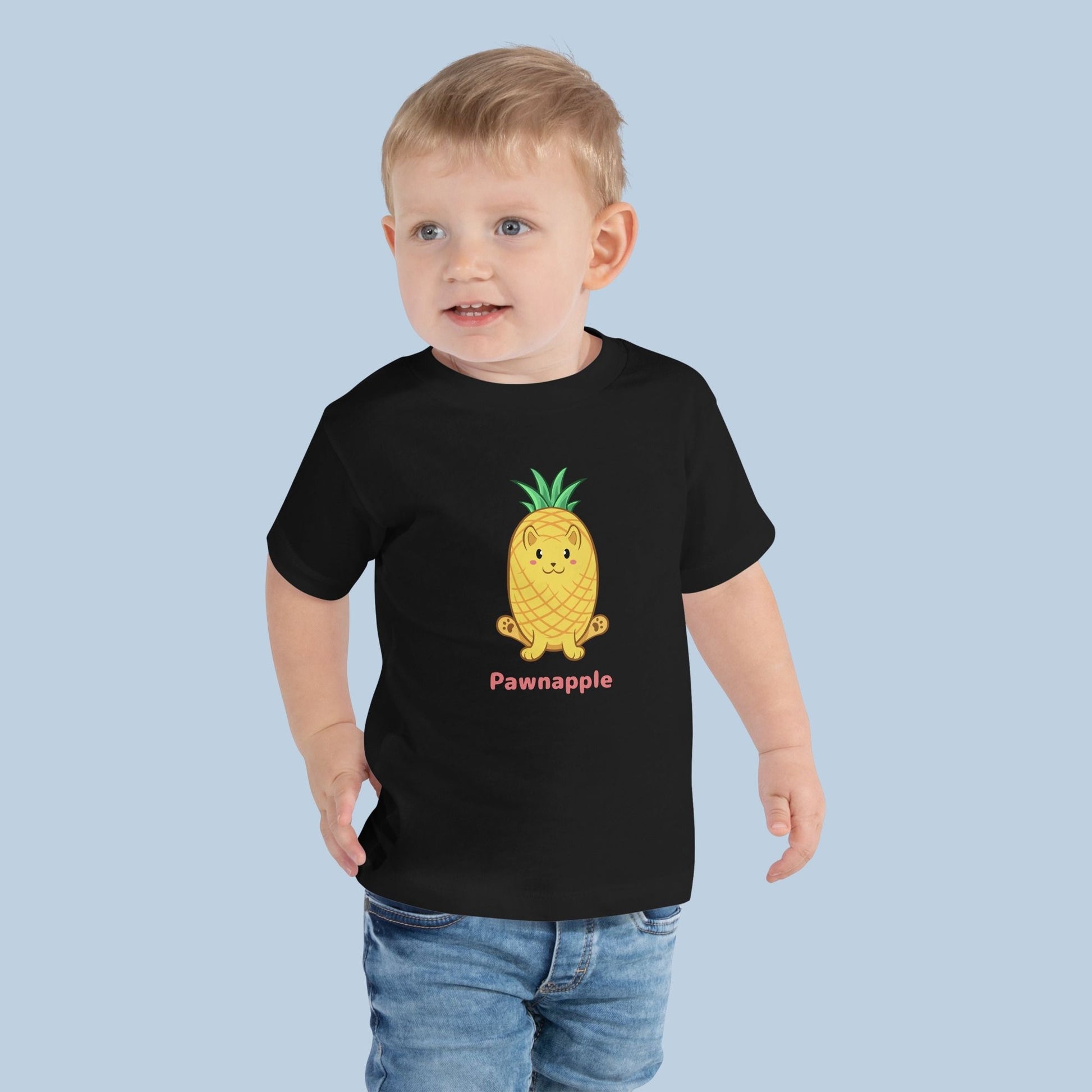 Toddler wearing a black Toddler T-Shirt with Pawnapple™ print. Pawnapple™ is a pineapple drawn as a cute cat.