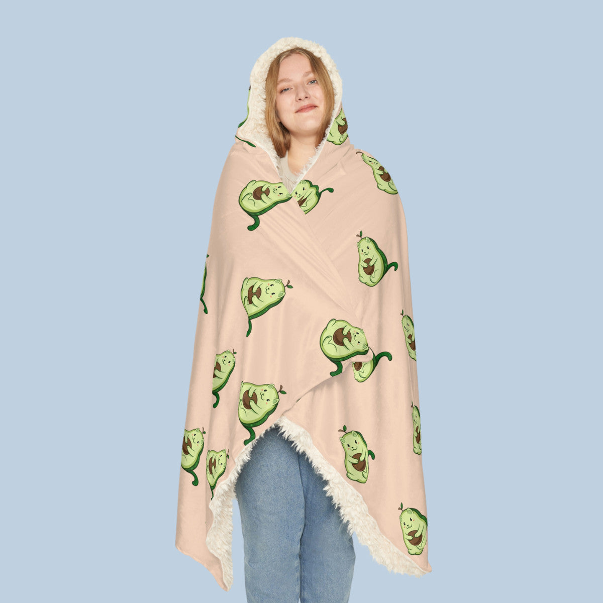 Happy woman wearing the beige Pawocado™ hooded sherpa blanket seen from front. Pawocado™ is an avocado drawn as a cute cat.