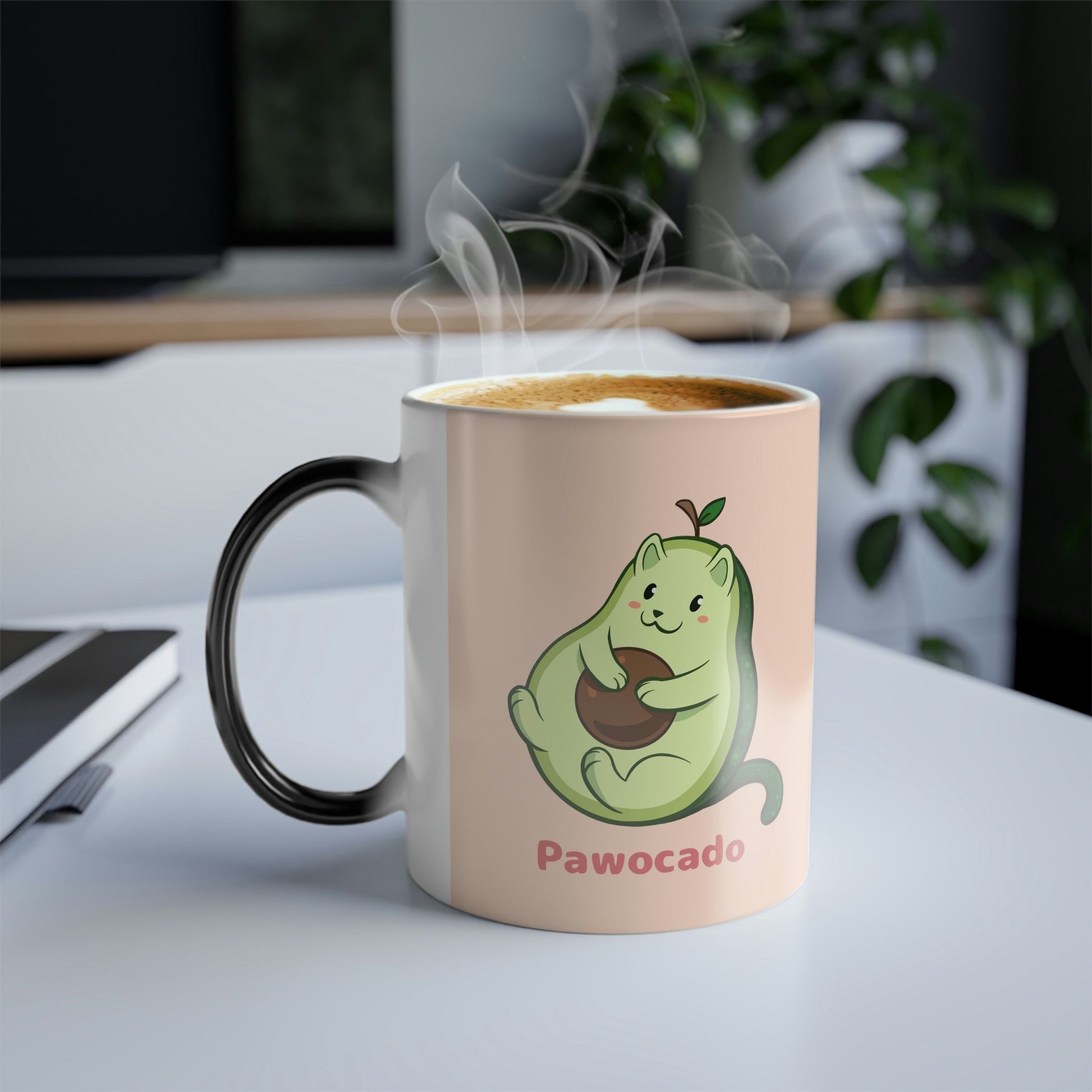 Beige Magic Mug with Pawocado™ print standing on an office desk. Pawocado™ is an avocado drawn as a cute cat.