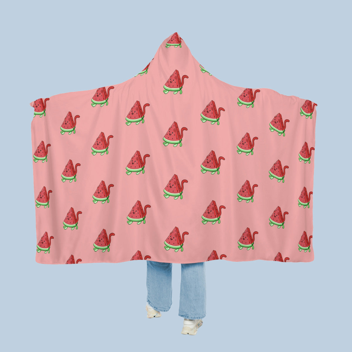 Happy woman wearing the pink Watermewlon™ hooded microfiber fleece blanket like a cape with arms stretched out seen from behind so that the full pattern is visible. Watermewlon™ is a watermelon drawn as a cute cat.