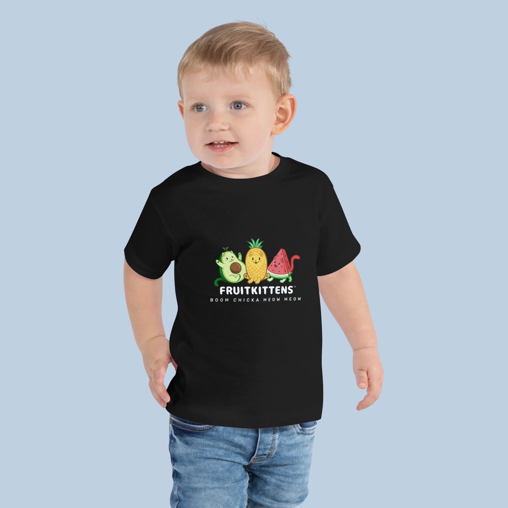 Toddler wearing a black Toddler T-Shirt with Fruitkittens™ logo. Fruitkittens™ are fruits drawn as cute cats. The logo features Pawocado™, Pawnapple™ and Watermewlon™.