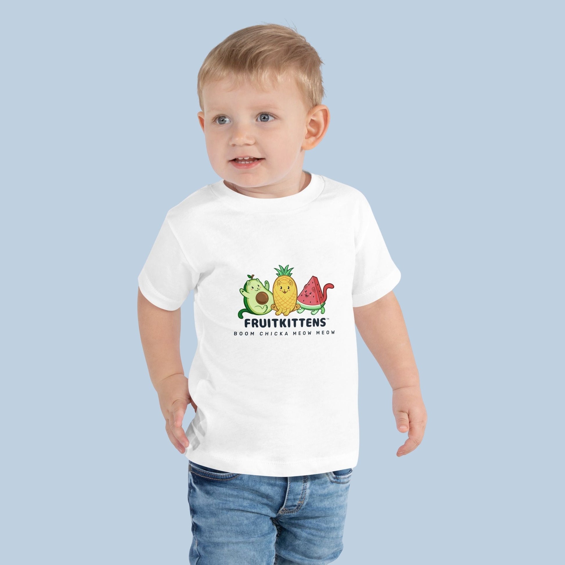 Toddler wearing a white Toddler T-Shirt with Fruitkittens™ logo. Fruitkittens™ are fruits drawn as cute cats. The logo features Pawocado™, Pawnapple™ and Watermewlon™.